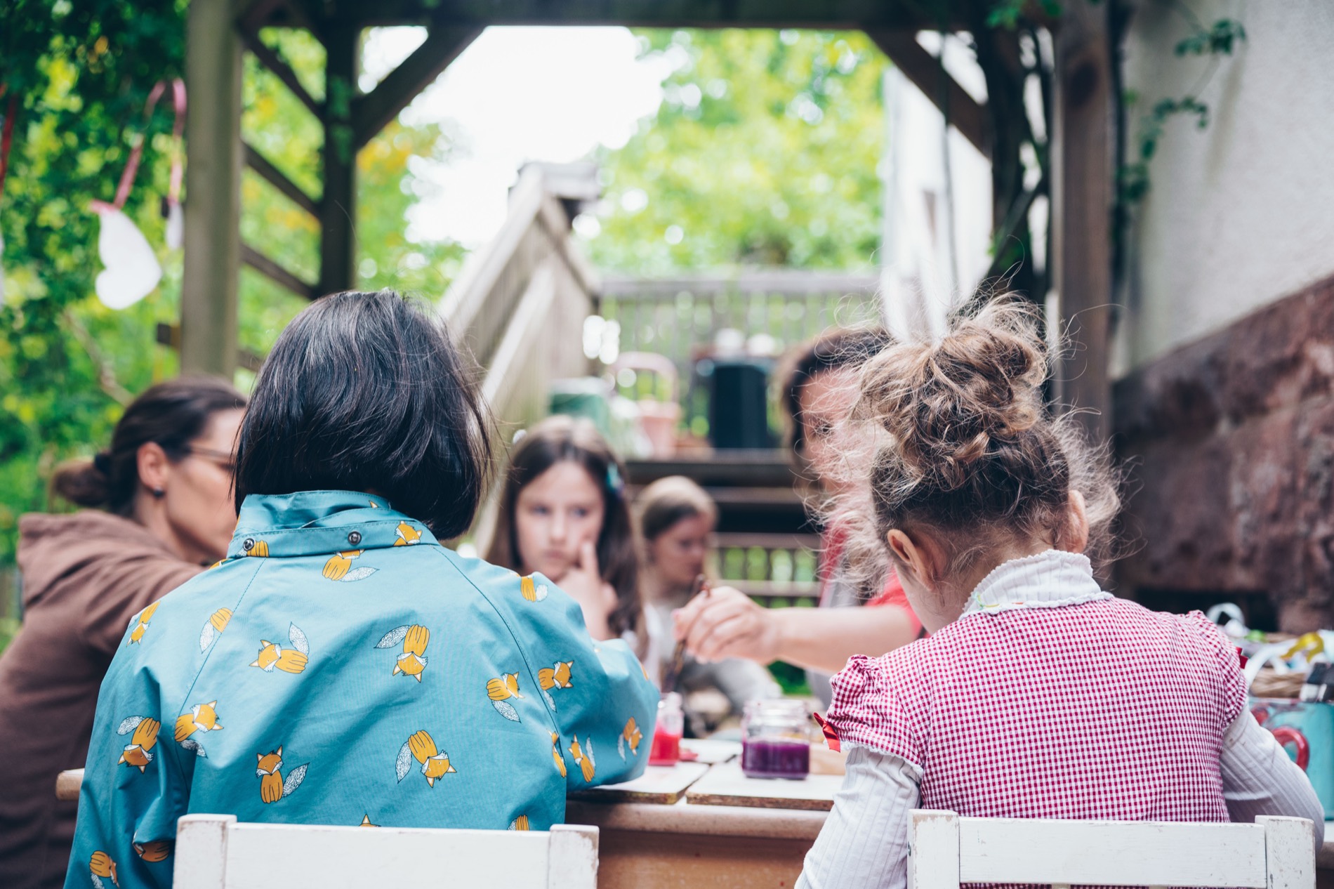 Kinder und Erwachsene an einem langen Tisch im Freien