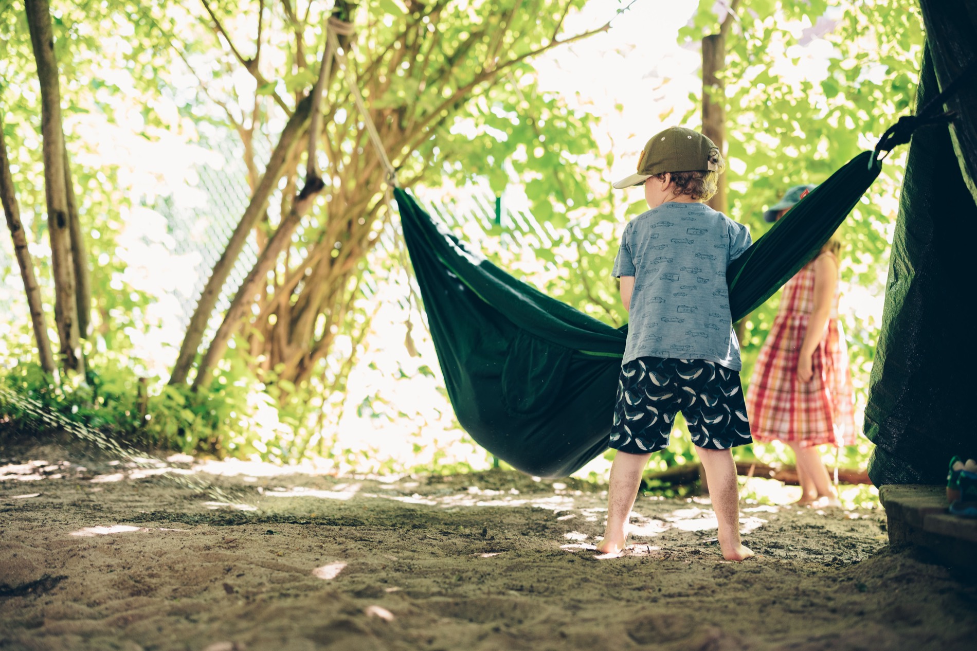Kinder spielen an einer Haengematte im Freien
